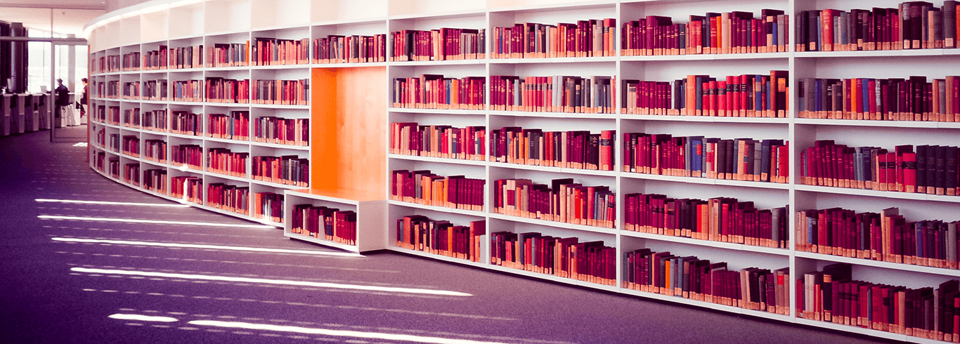 a collection of books on a curved, white bookshelf 