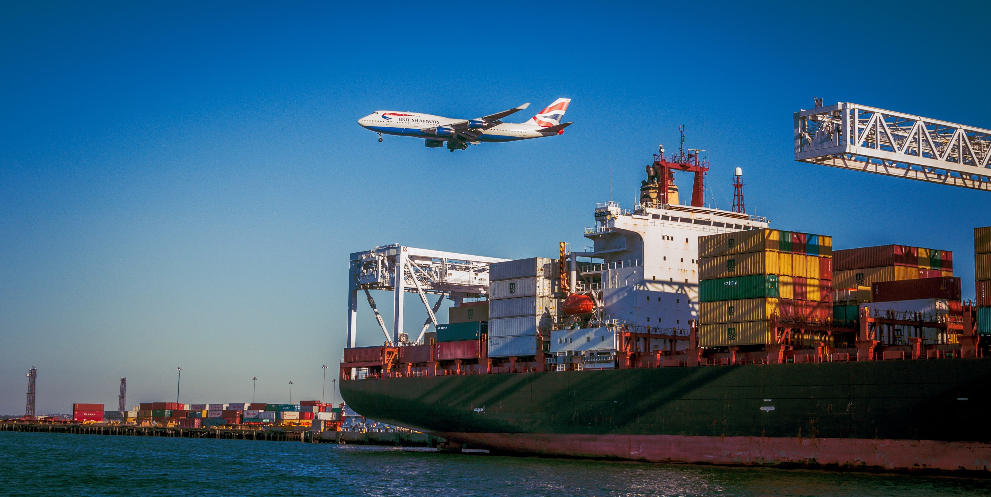 Cargo ship with containers, plane flying in the background
