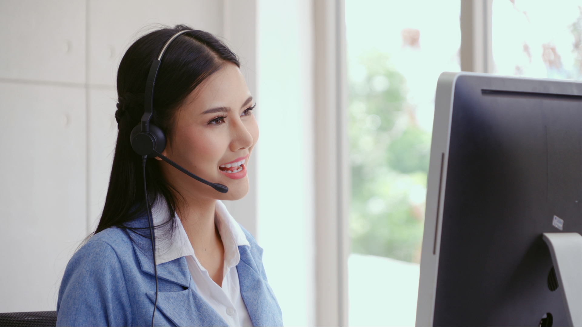 Customer support agent or call center with headset works on desktop computer