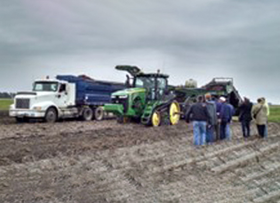 Blue truck and green tractor with group of people