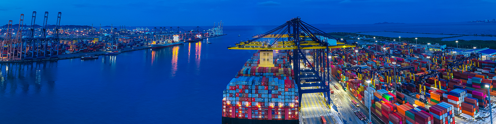 Image of cargo containers, and a ship with containers sitting in water. 