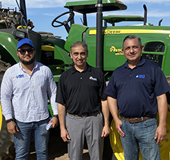 Three men standing in front of a tractor
