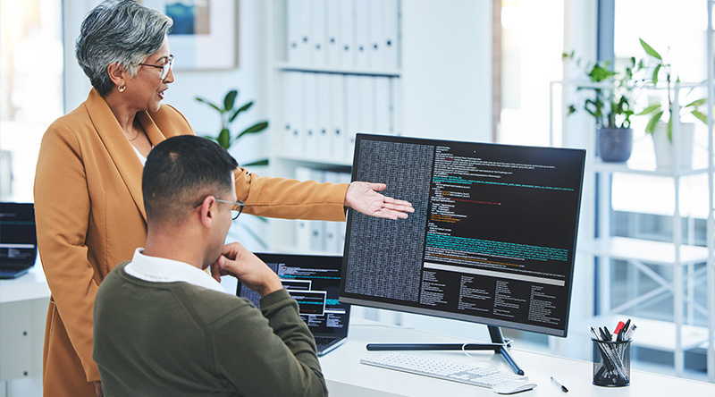 manager coaching employee looking at screen full of code