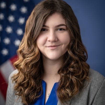 Headshot of Lauren Shelton with U.S. flag behind her.