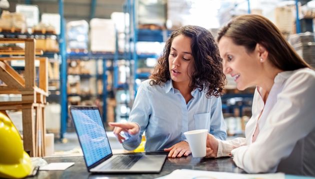 A photograph of warehouse workers looking at a computer.