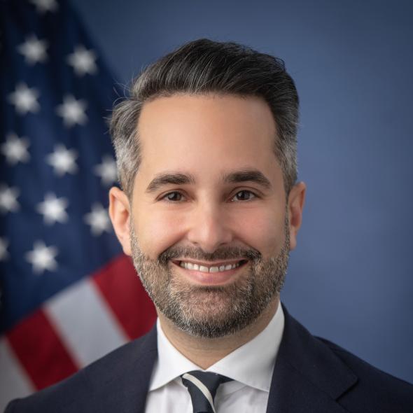 Headshot of Zachary Learner, with U.S. flag in background