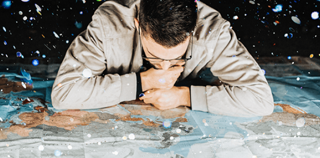 close up of a man studying a map laid out on a floor