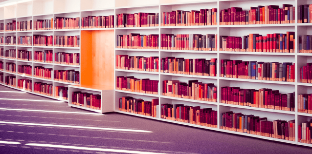 a collection of books on a curved, white bookshelf 