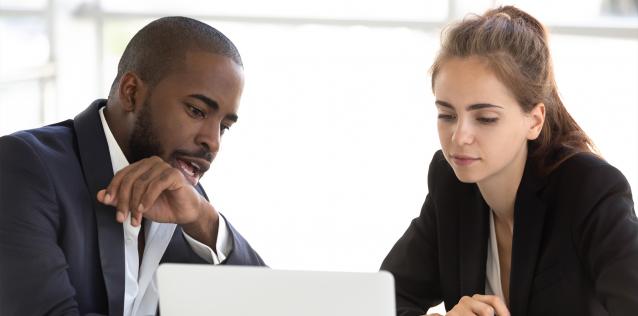 Man showing woman information on laptop.