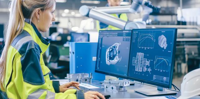 Woman wearing a yellow work jacket is using a computer to design an engine or rotor