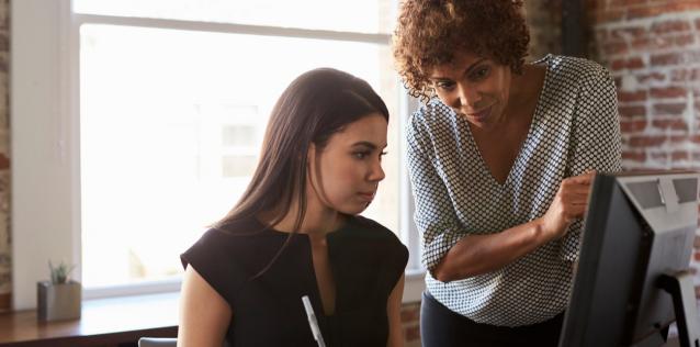 Two Businesswomen Working On Computer In Office.