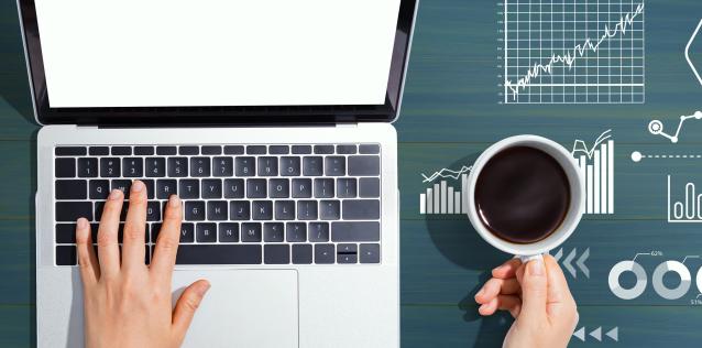 Woman typing on laptop, coffee cup