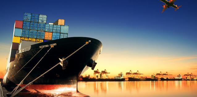 Cargo ship with multi-colored containers on the ocean with sunset