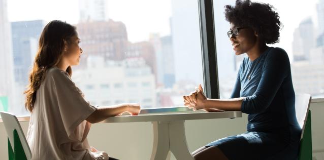 two woman sitting talking in table