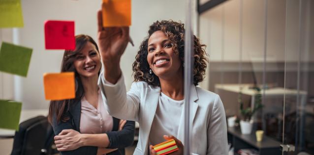 Two woman using sticky notes to brainstorm and plan