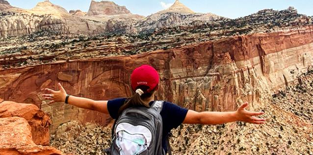 lady standing with outstretched arms, at top of mountain