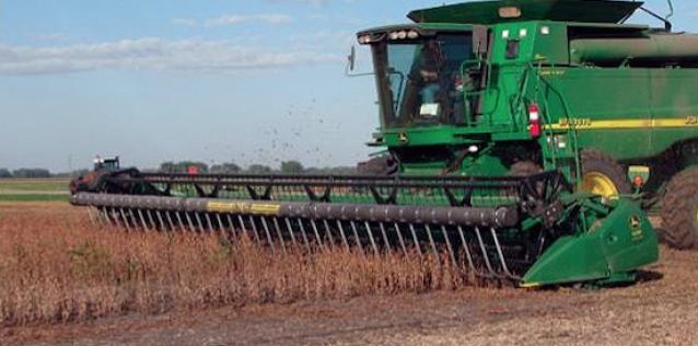 Large Agricultural grain collector plowing a field of wheat during the day