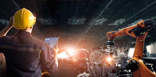 man with hardhat observing advanced manufacturing machinery