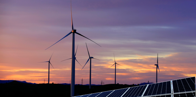 Sunset behind giant windmills producing energy. 