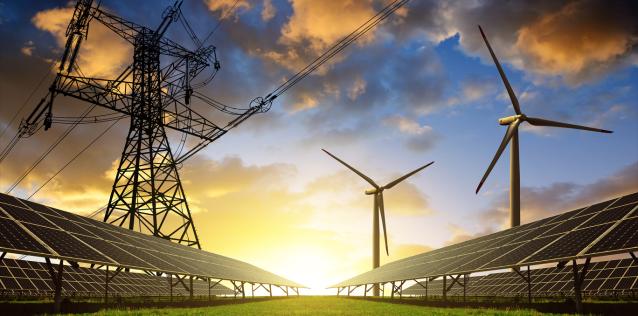 Image of wind turbines, solar panels, and electricity lines against a sunset