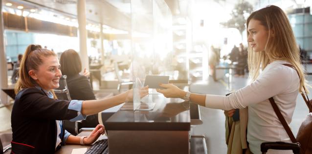 A woman hands a passport to a passport control agent in an airport