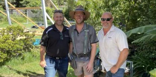 Three men standing in a grassy area in Australia