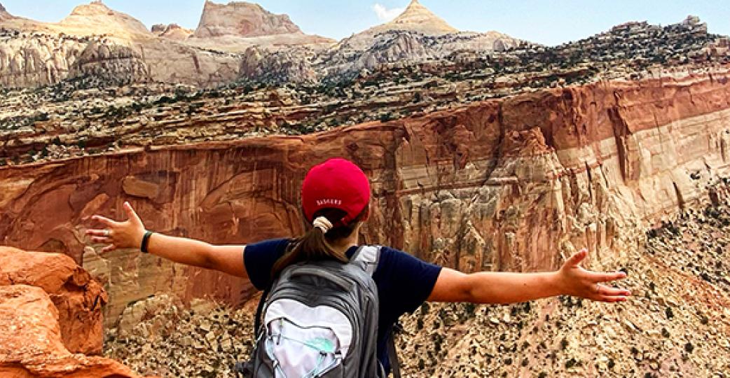 lady standing with outstretched arms, at top of mountain